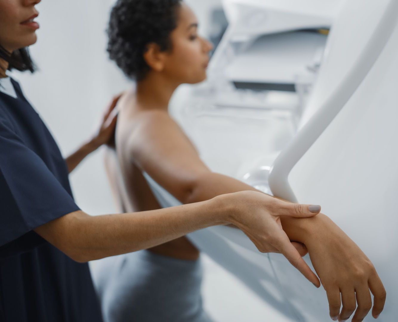 A healthcare professional assists a patient during a mammogram procedure in a clinic.
