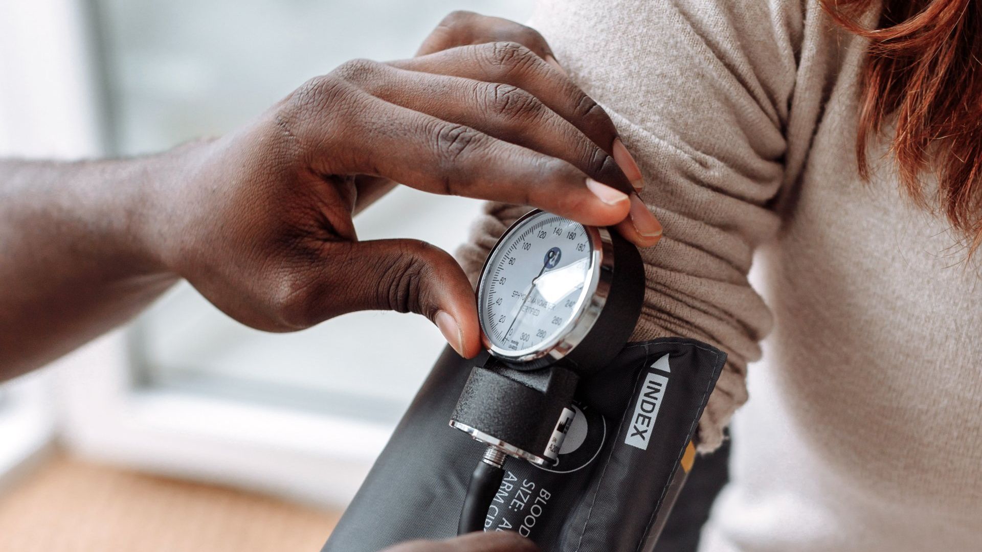 A medical professional checks a patient’s blood pressure using a manual sphygmomanometer.