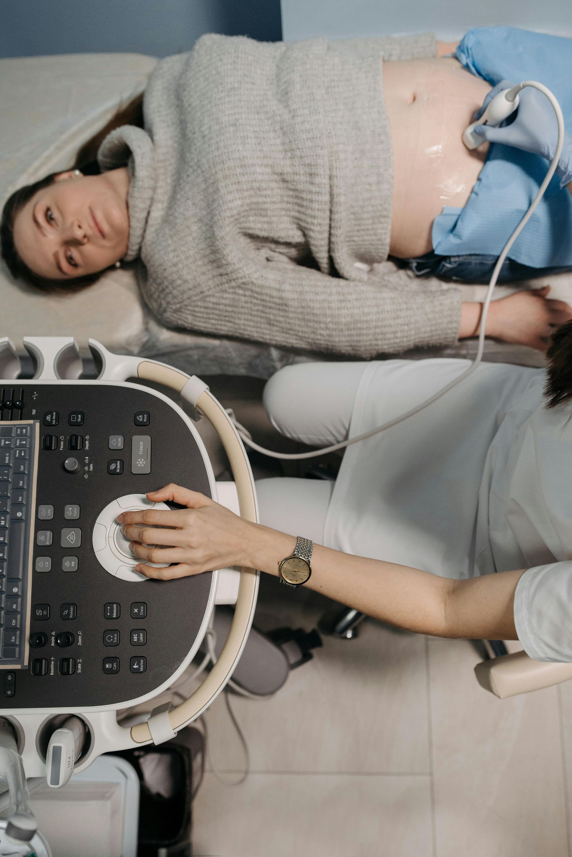 A patient lying on an examination table while a medical professional uses an ultrasound machine to scan their abdomen.