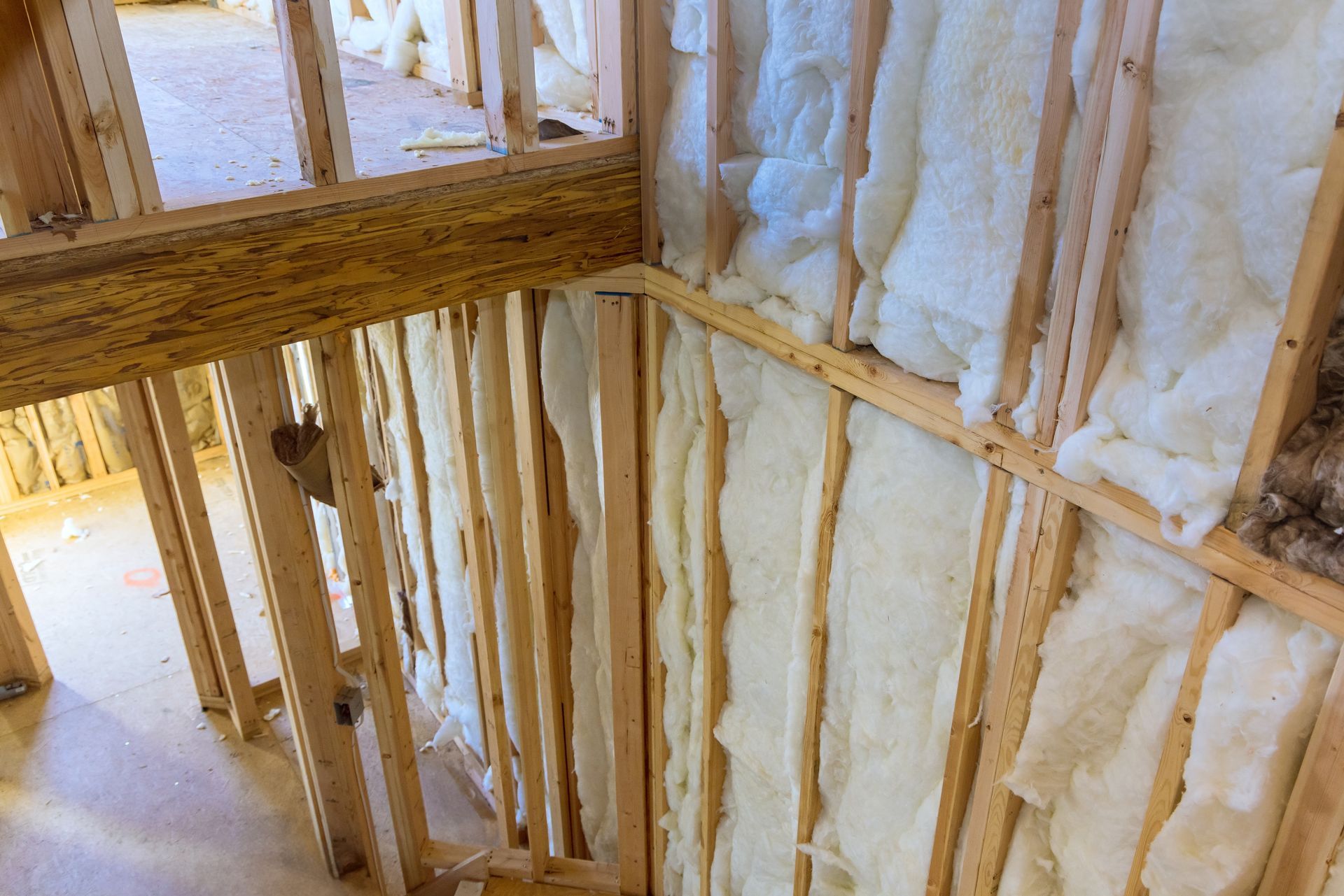 Insulated wall framing with exposed wooden studs and white spray foam insulation inside a building
