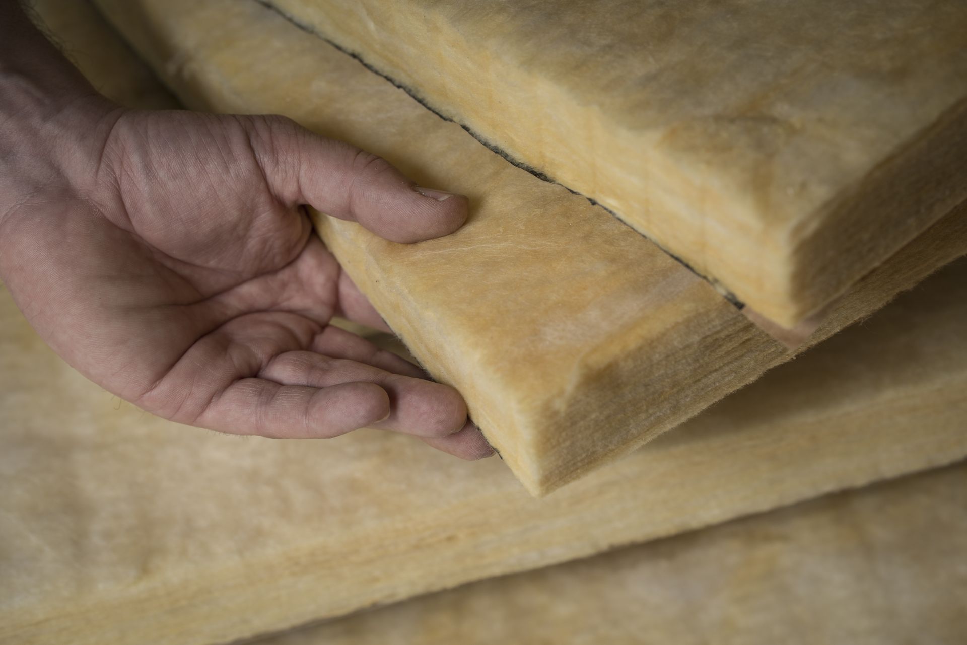 Hand holding a stack of yellowish insulation foam panels