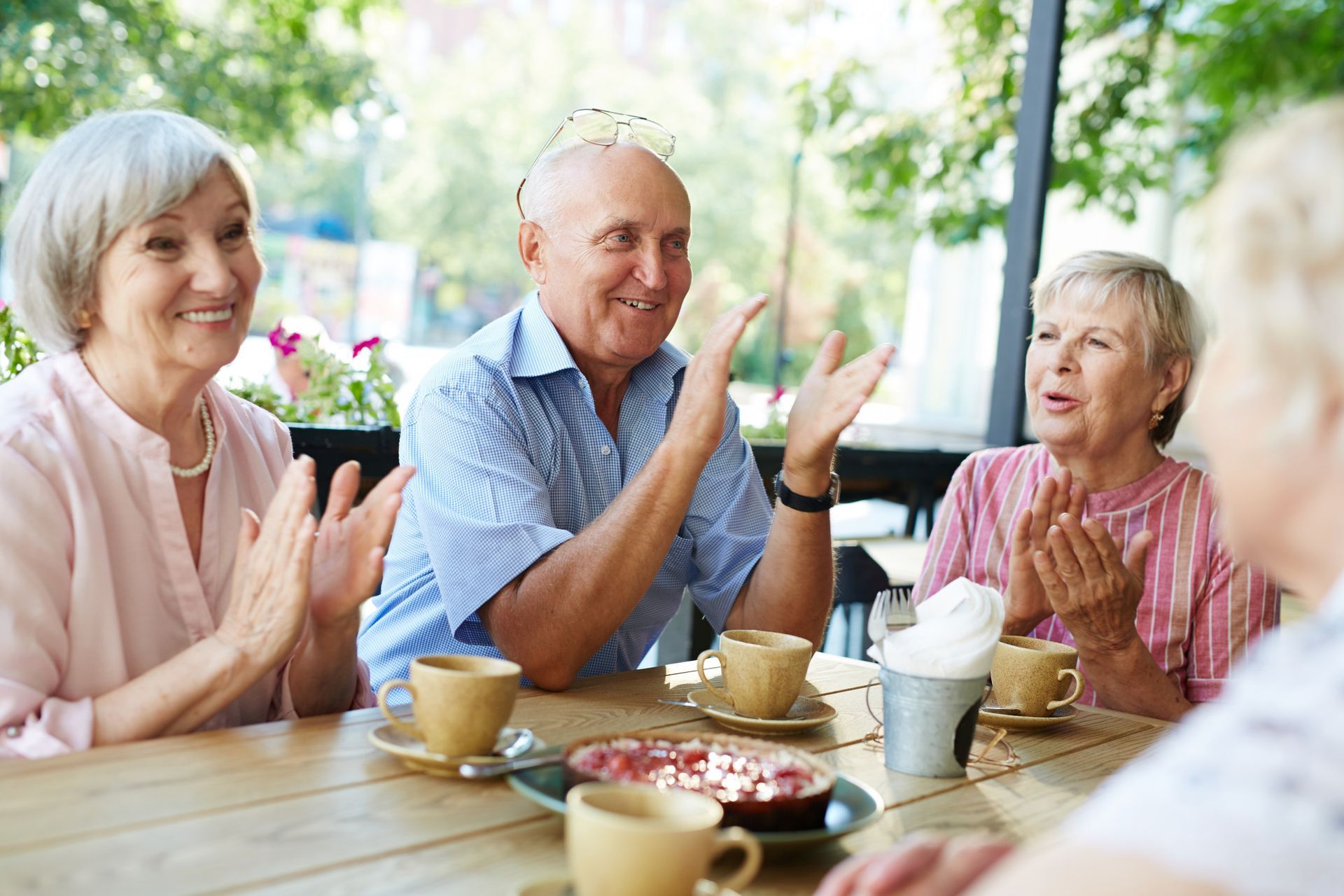 A group of elderly people are sitting at a table with cups of coffee.