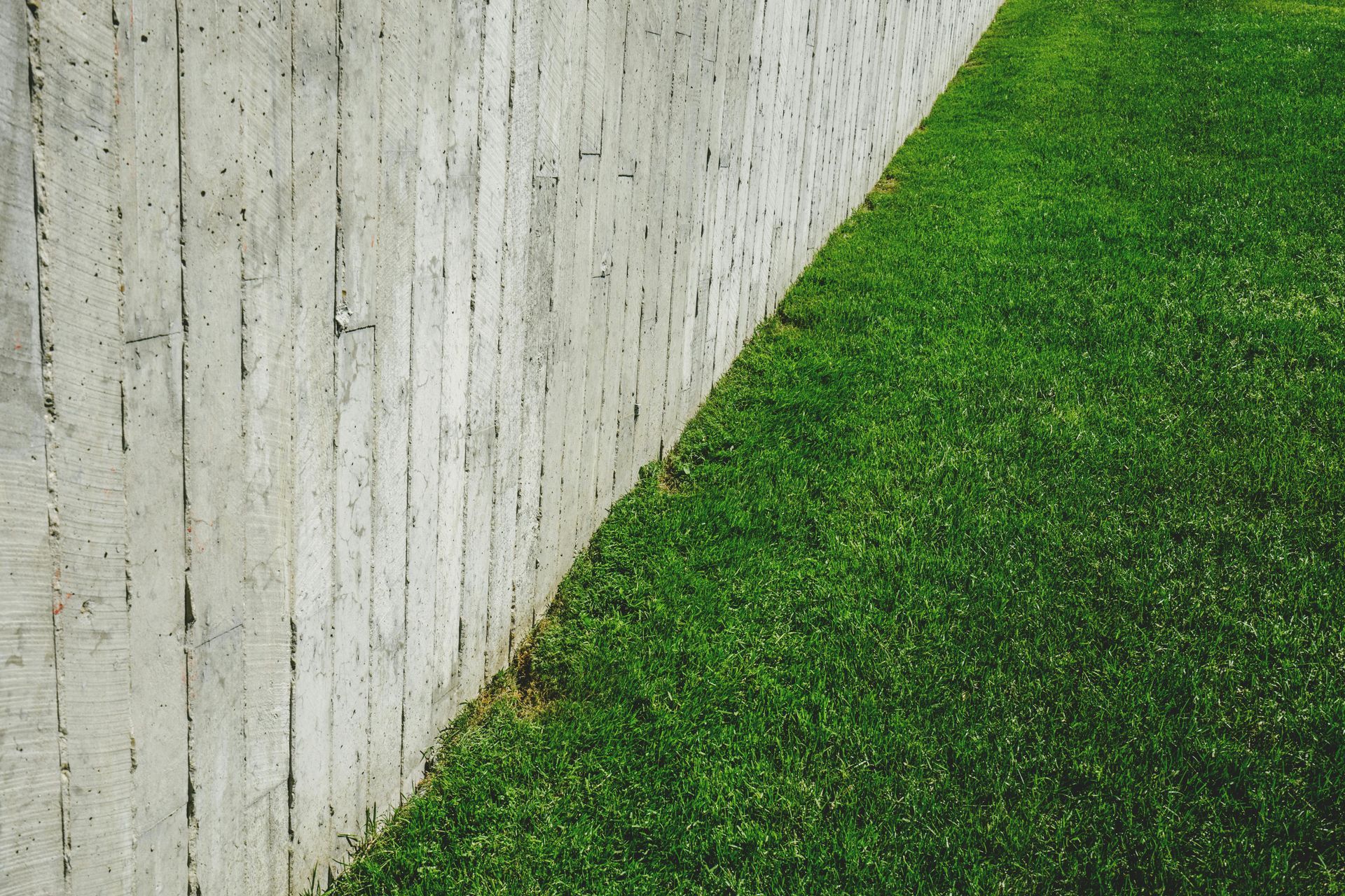 A concrete fence surrounds a lush green lawn.