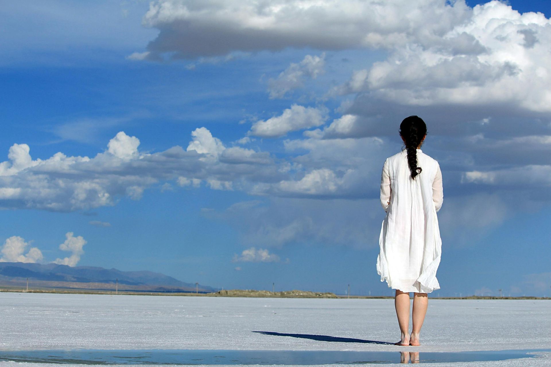 A woman is standing on a lake looking at the sky.