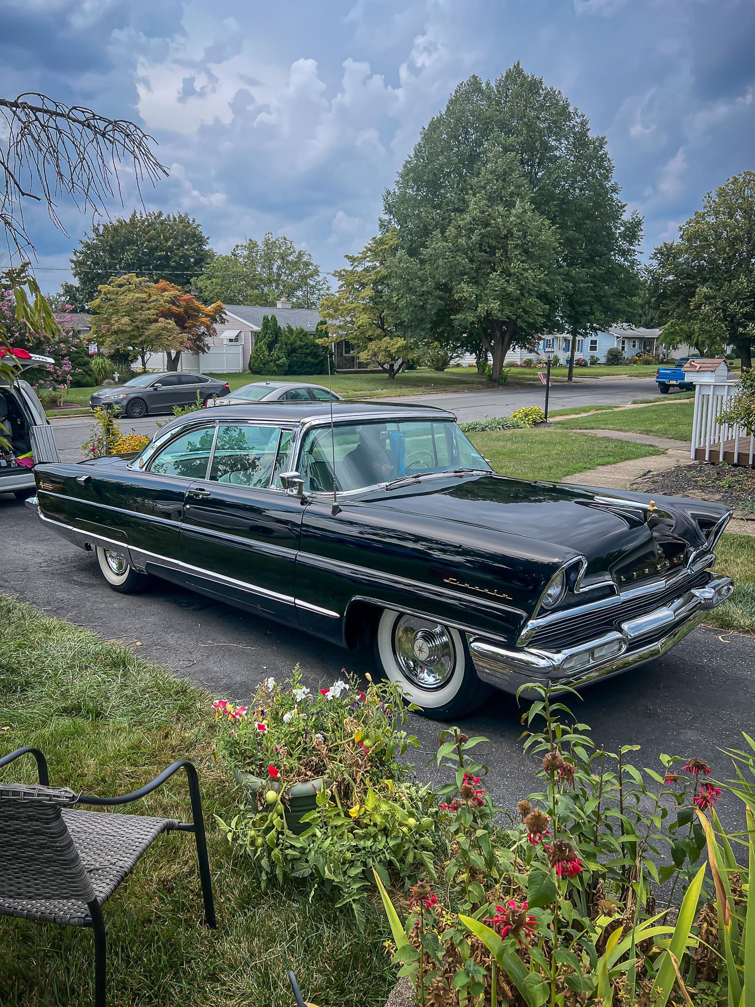 A black car is parked in the driveway of a house.