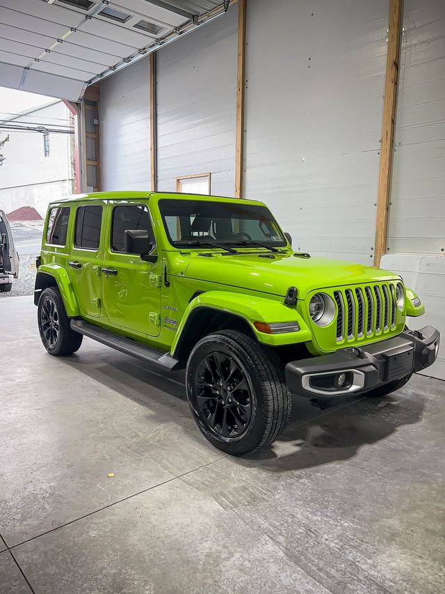 A green jeep wrangler is parked in a garage.