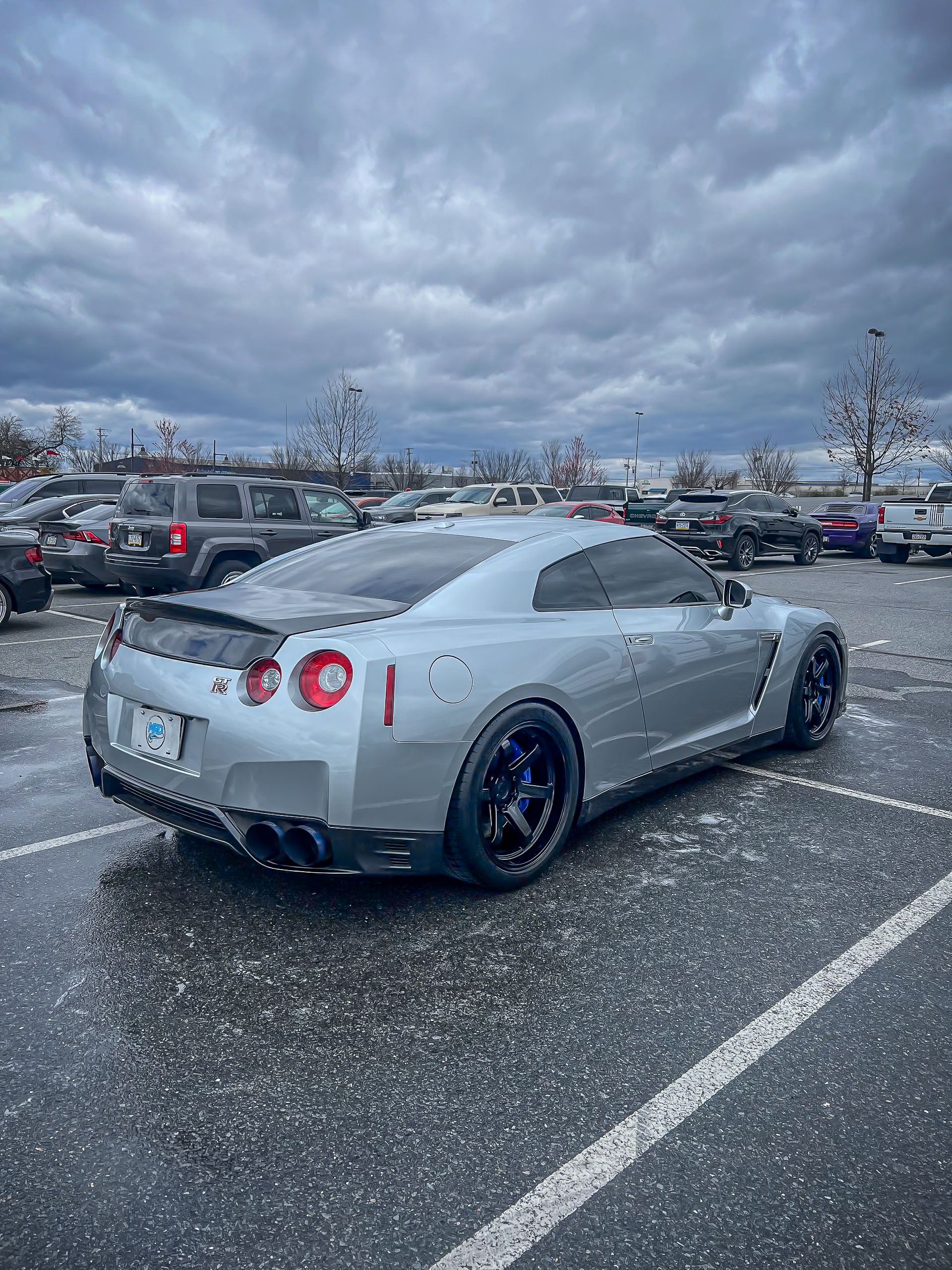 A silver nissan gtr is parked in a parking lot.