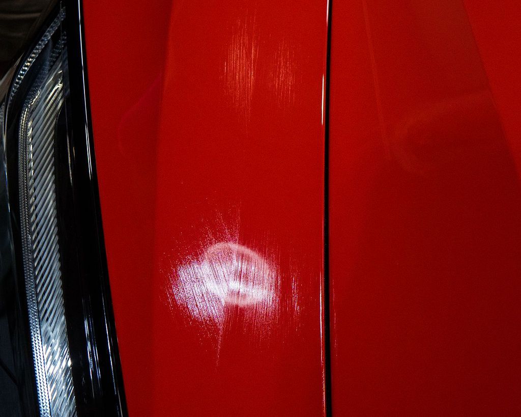 A close up of a red car with a white stain on it.