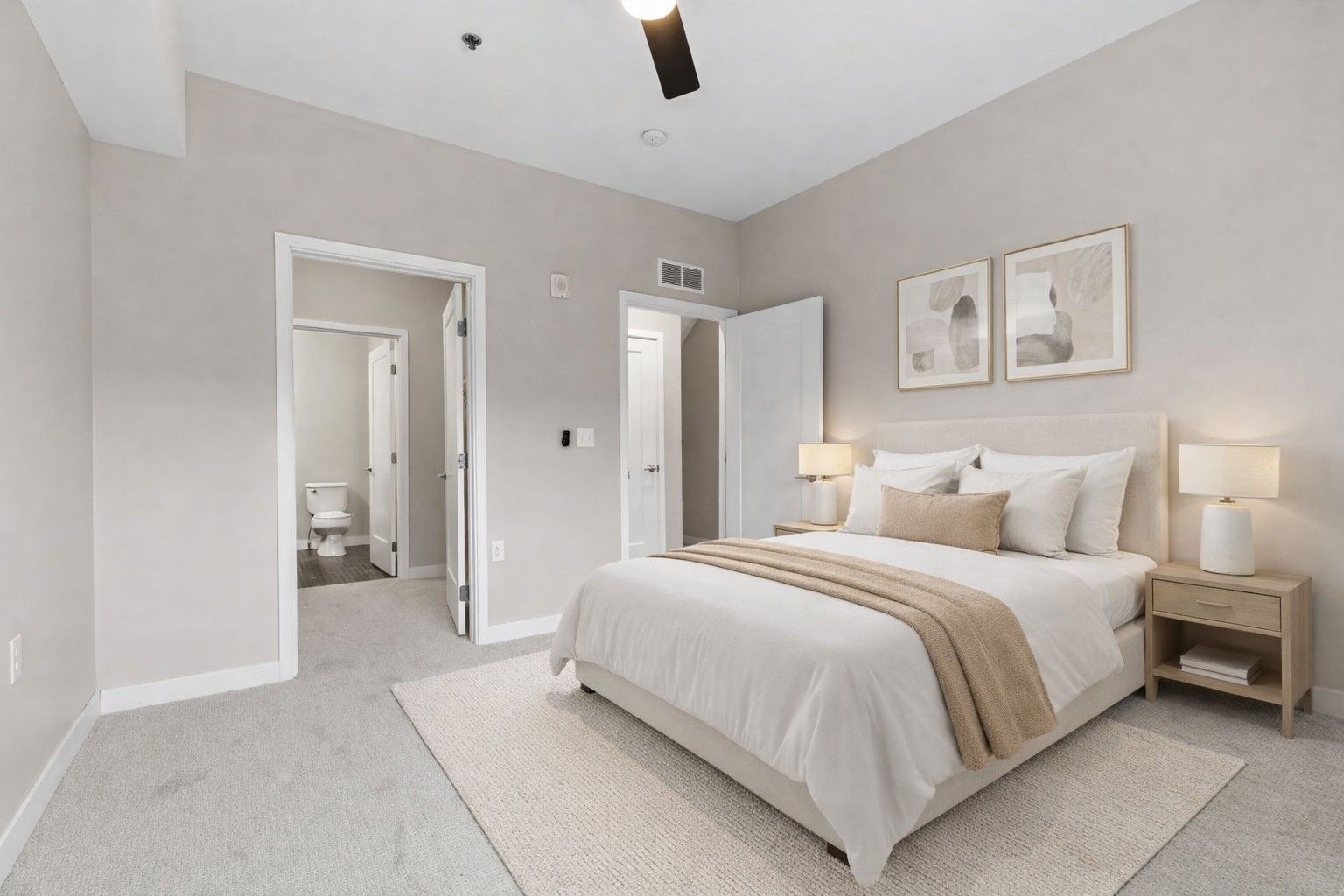 A bright, minimalist bedroom here at Maverick with a queen bed, light-toned bedding, two framed prints, and an en-suite bathroom.