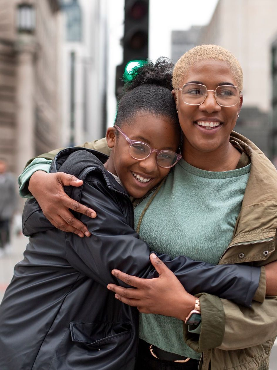 Two women are hugging each other on a city street.