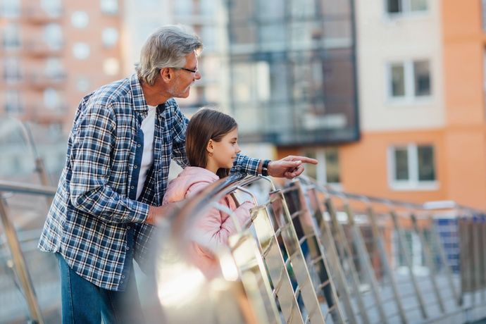 A man and a little girl are standing on a balcony.