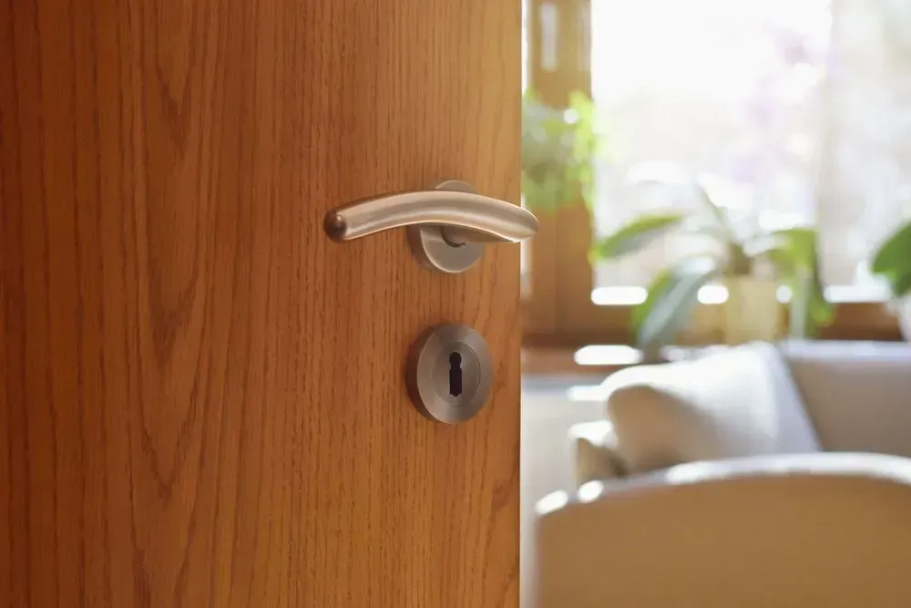 A Wooden Door with A Silver Handle Is Open to A Living Room — Lock & Door in Wodonga, VIC