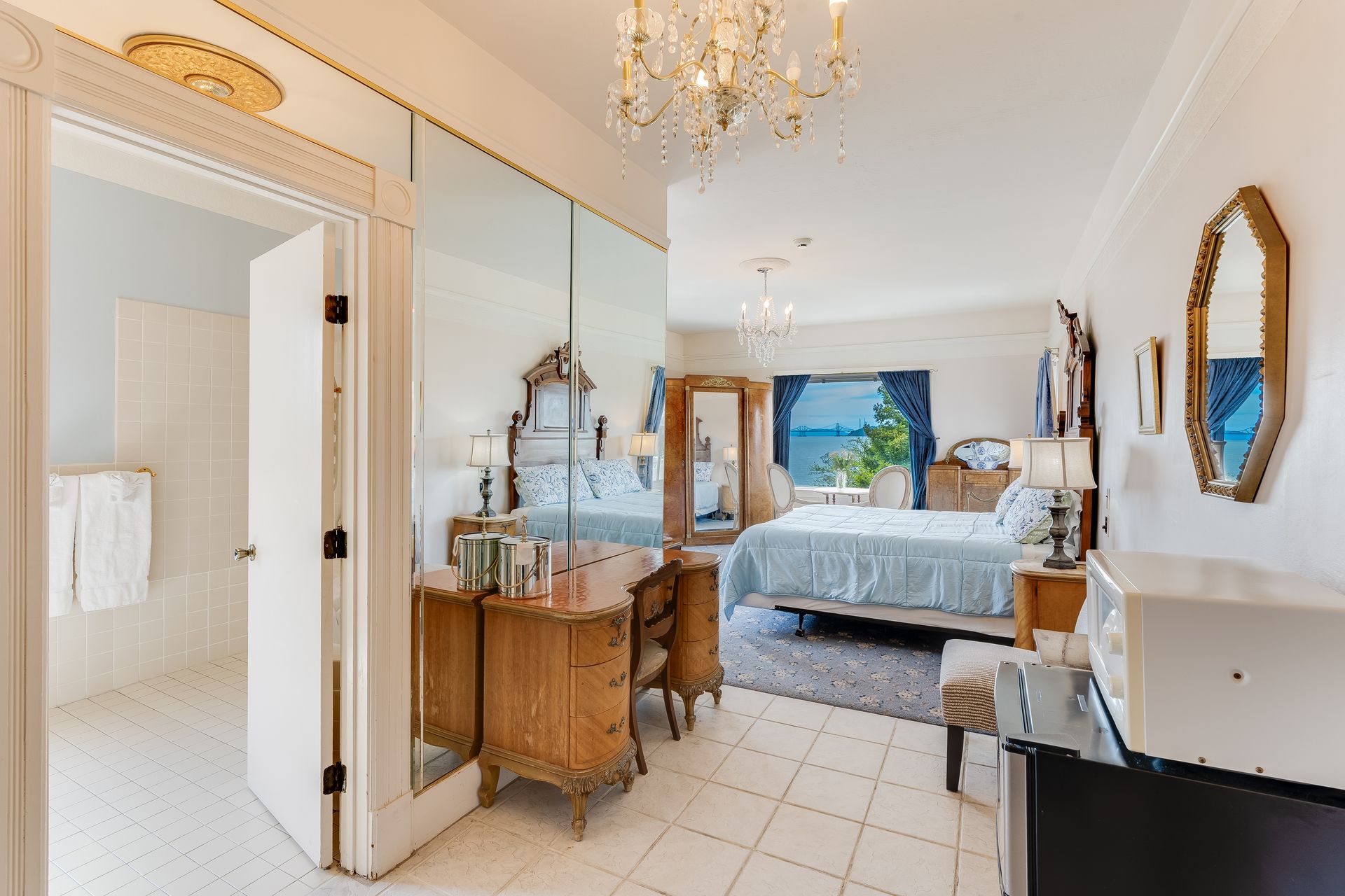 Bedroom with a full wall mirror, vanity, chandelier, and a view of the water.