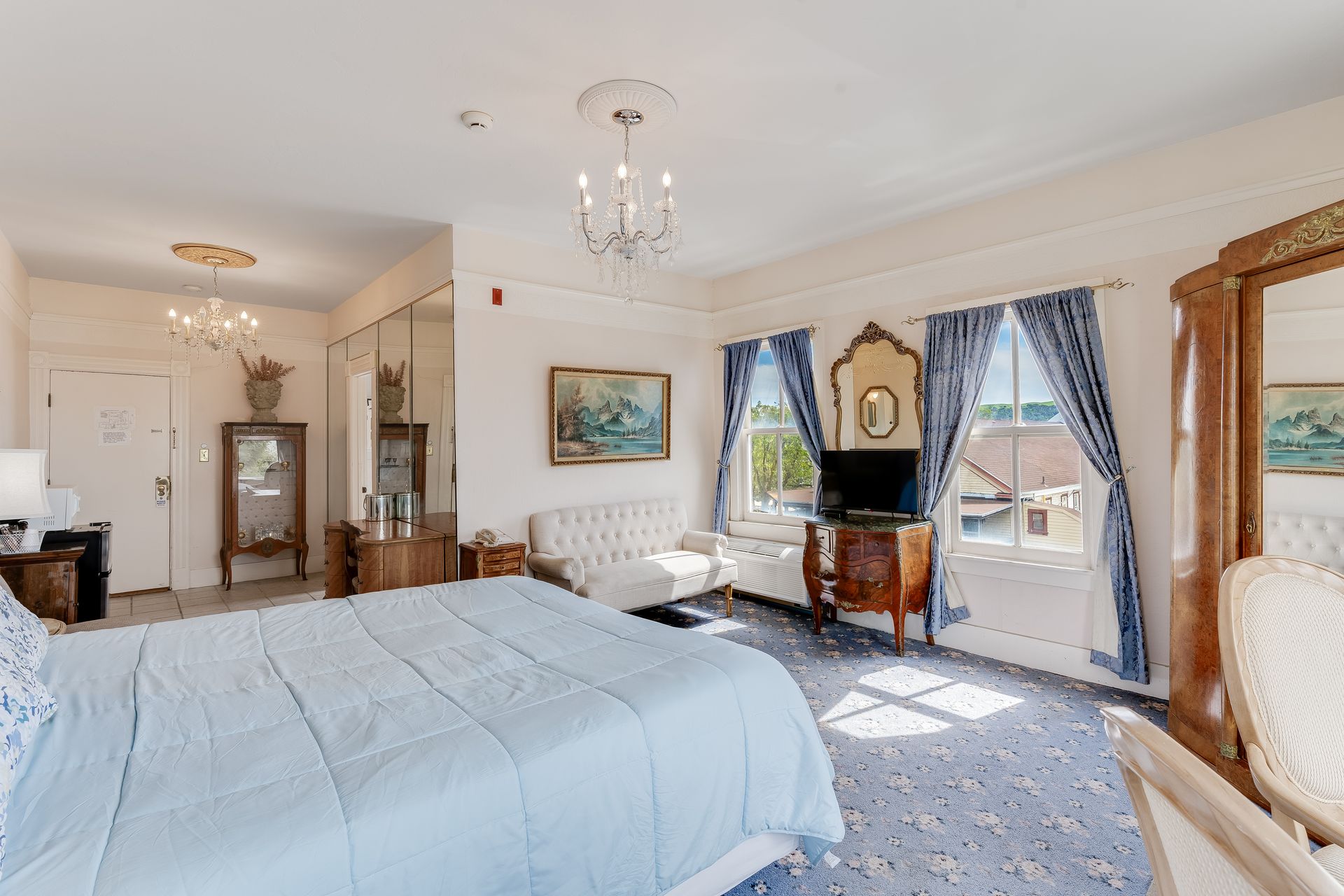 Spacious hotel room with a bed, seating area, and a balcony with a view.