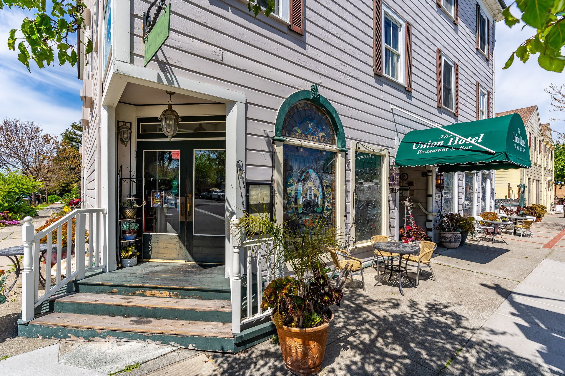 Exterior of a light gray building with a teal awning that says 