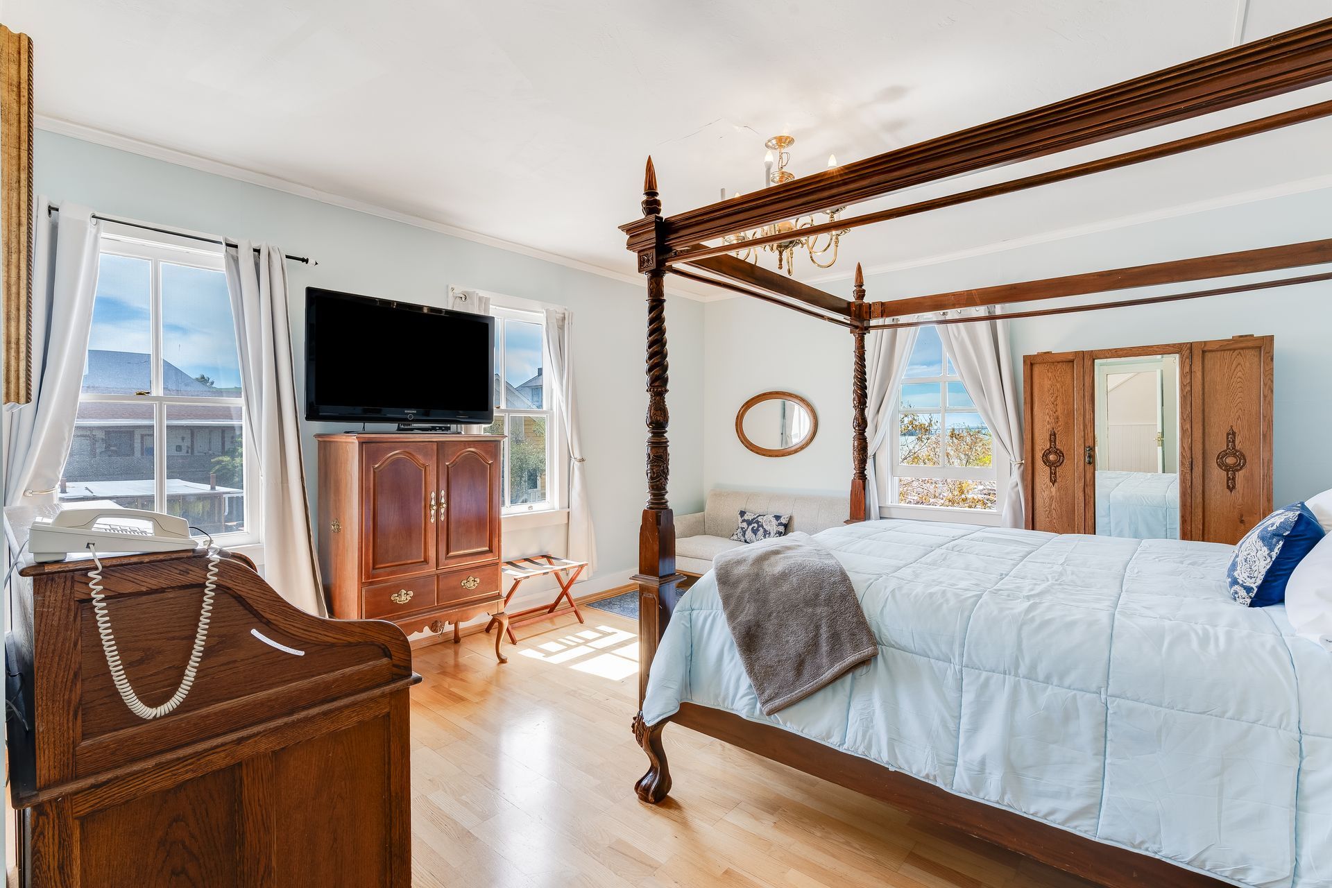 Bedroom with four-poster bed, wood furniture, and large windows overlooking a mountain view.