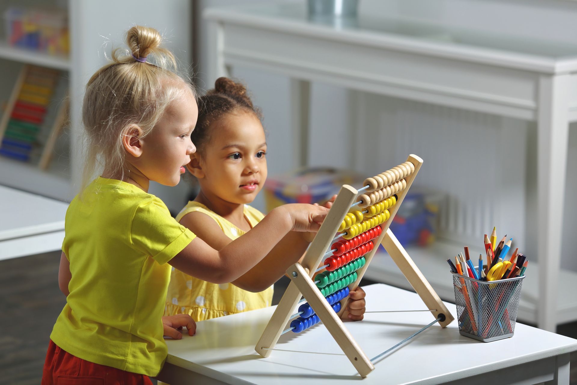 Two children using an abacus, learning math at a table, indoor setting.