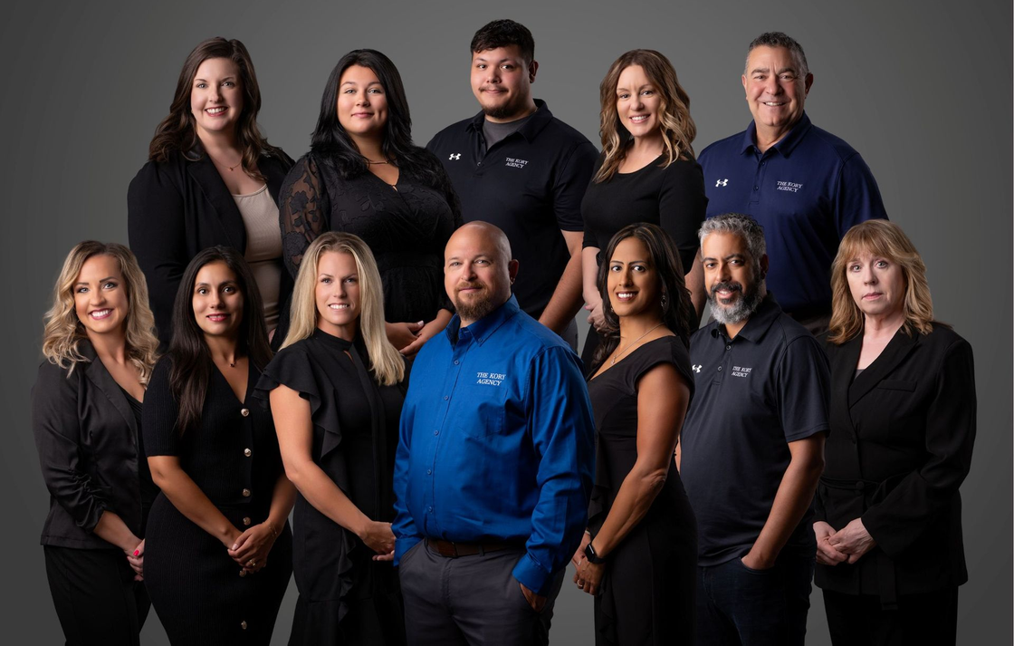 Seven people stand in a studio, smiling and posing against a black background.