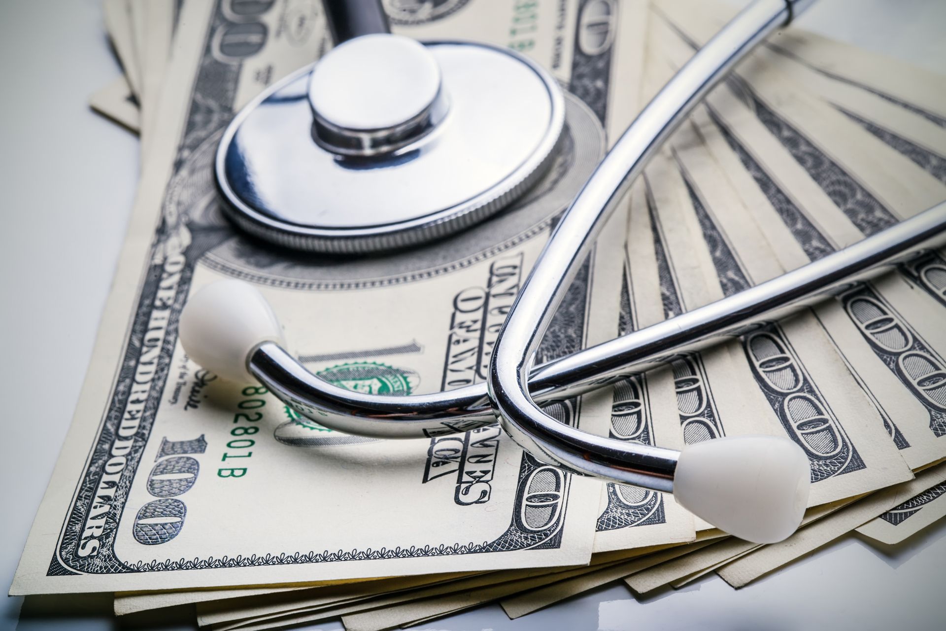 A stethoscope is laying on top of a pile of money