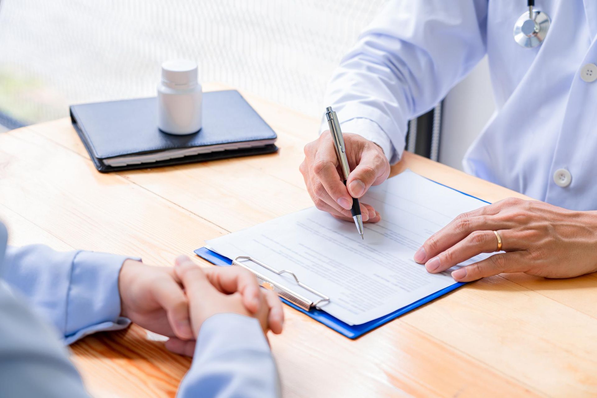 A doctor is writing on a clipboard while talking to a patient.