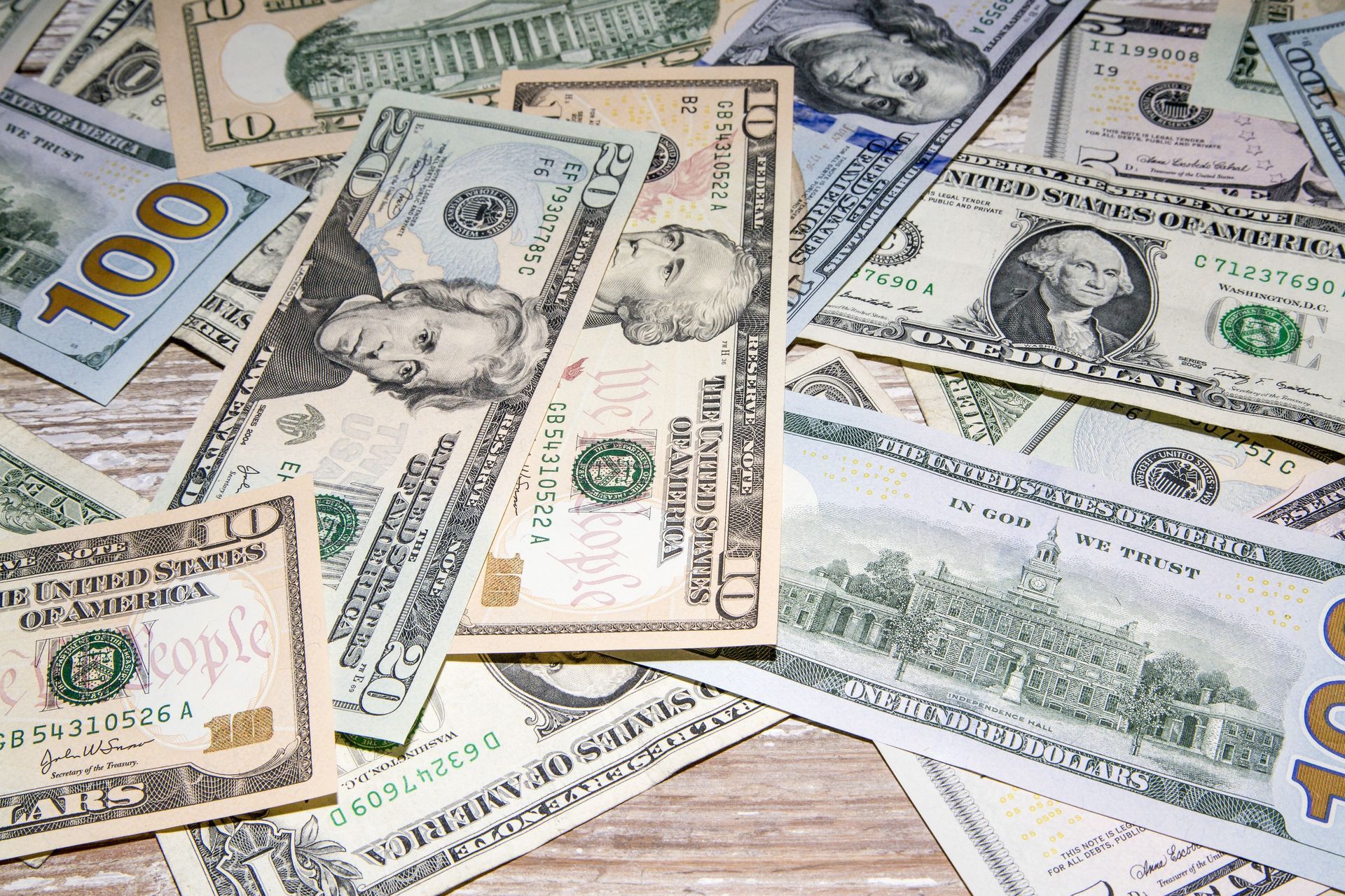 A pile of dollar bills on a wooden table