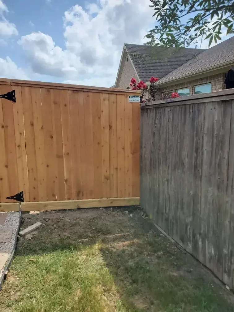 A wooden fence is in the backyard of a house.