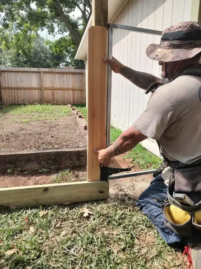 A man is measuring a wooden post with a tape measure.