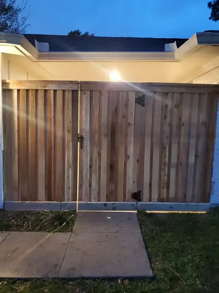 A wooden fence is surrounding a house at night