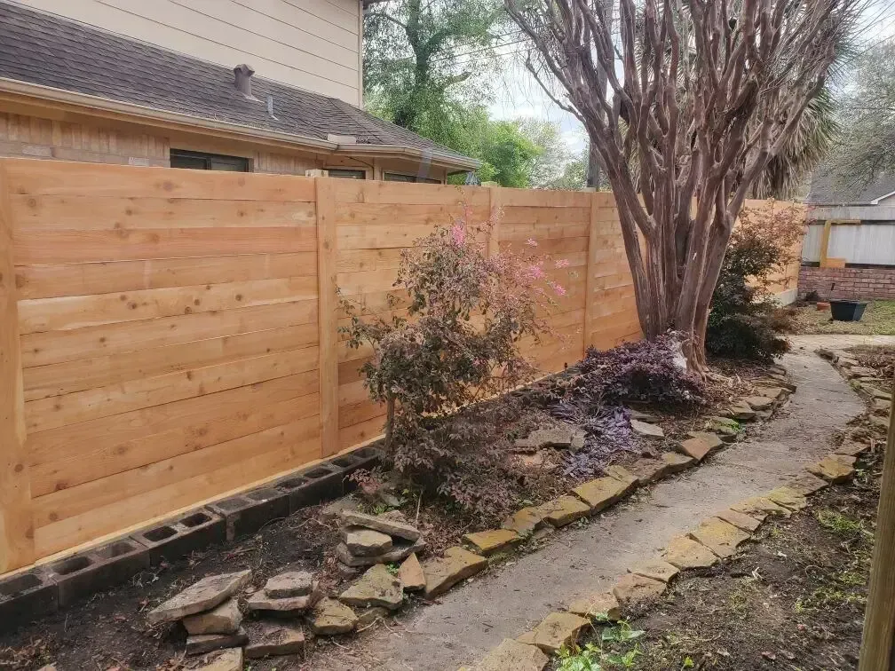 A wooden fence is in the backyard of a house.