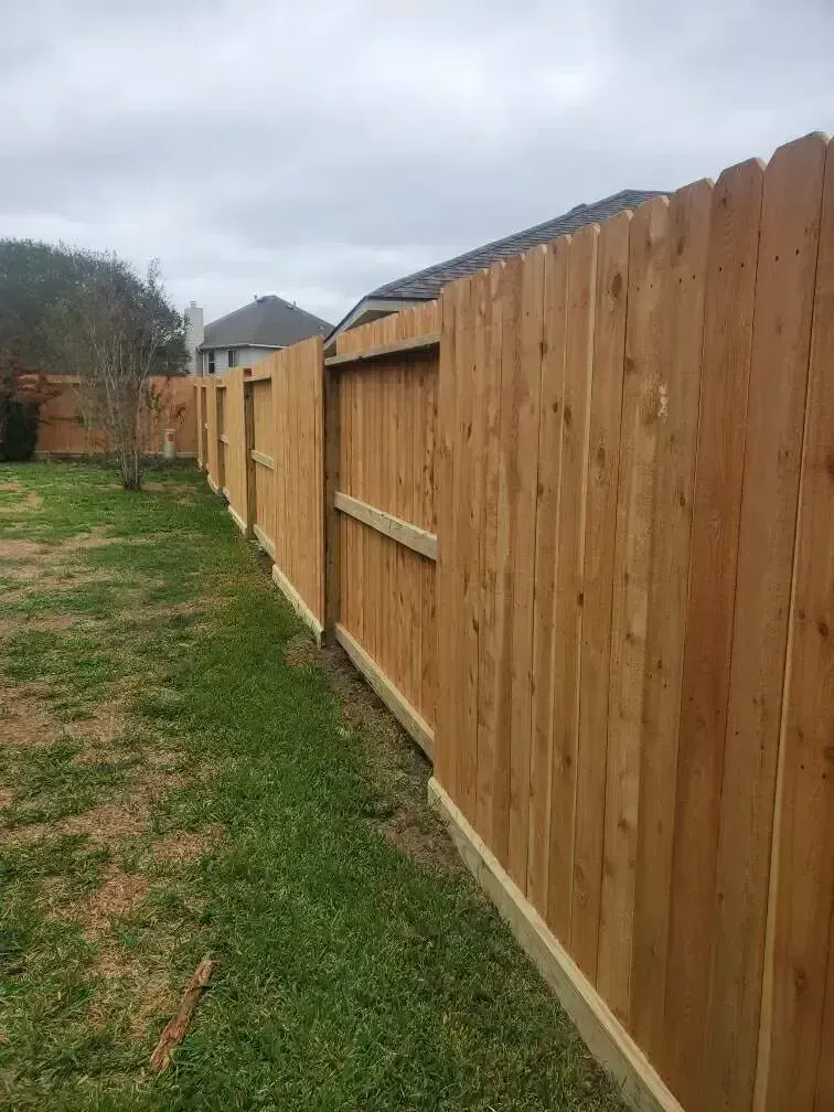 A wooden fence with a gate in the backyard of a house.