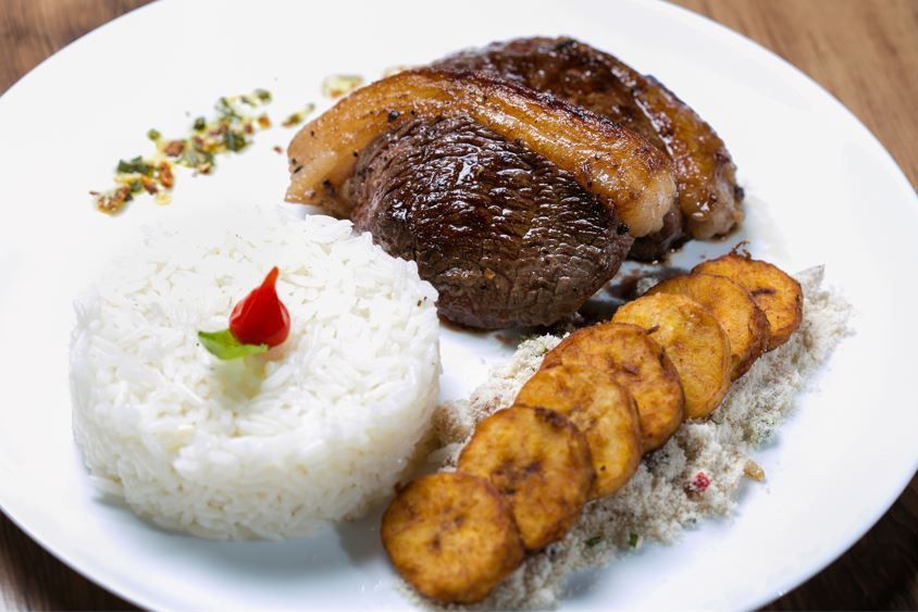 Prato de frutos do mar em uma tigela com caranguejo, lagosta, verduras e mariscos sobre uma mesa escura.