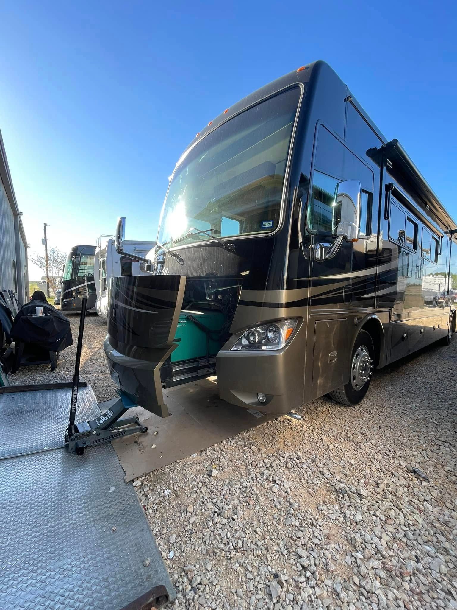 Large tan and black luxury motor coach parked inside a warehouse or garage.