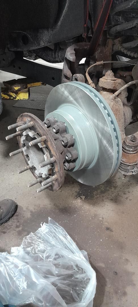 A close up of a brake disc on a truck in a garage.