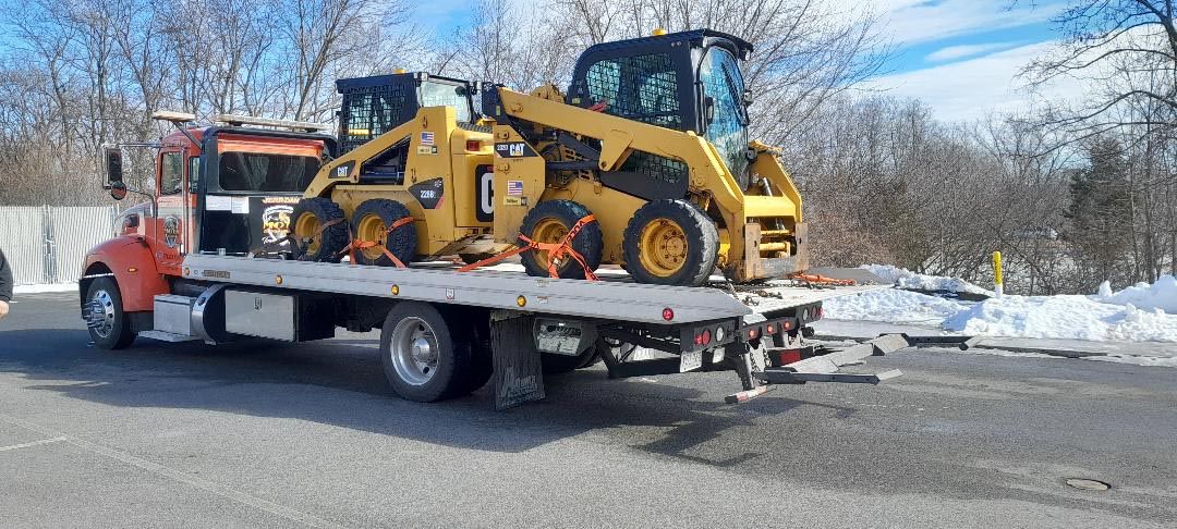 A tow truck is carrying a bulldozer on the back of it.