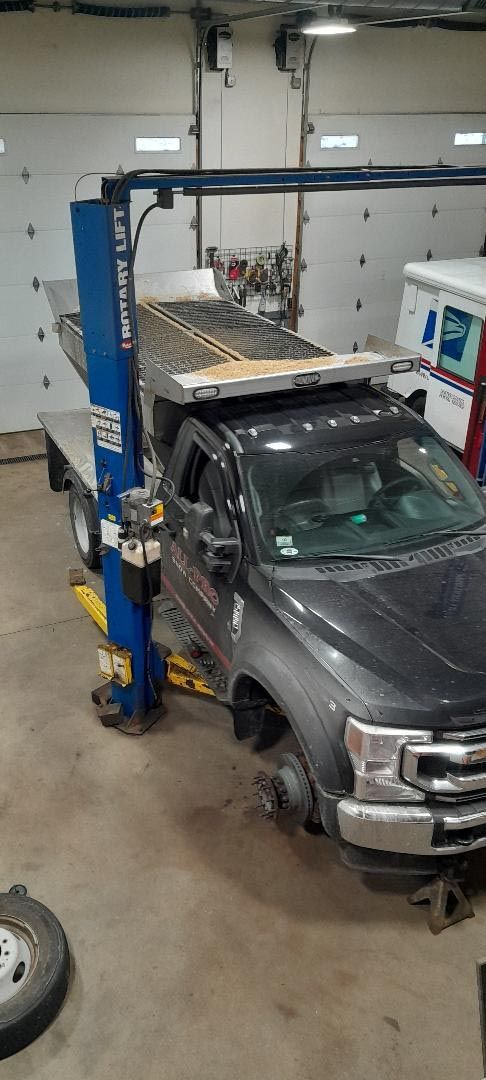 A truck is sitting on a lift in a garage.