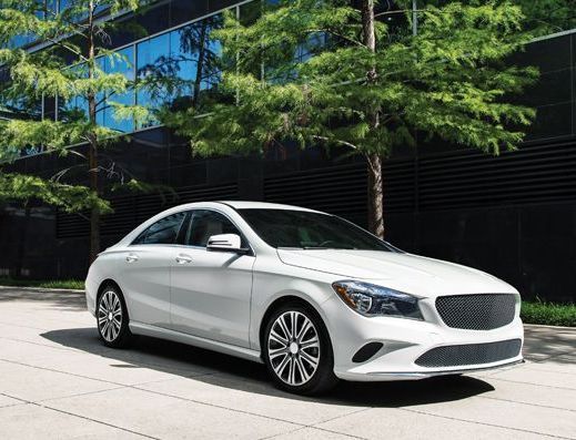 Silver sedan parked outside a modern building with trees reflecting on the windows