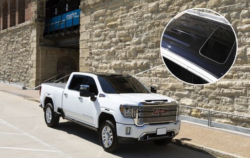 White pickup truck parked beside a stone wall, with a close-up inset of the truck’s windshield frame.