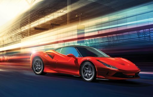 Red sports car speeding through a blurred city street at dusk