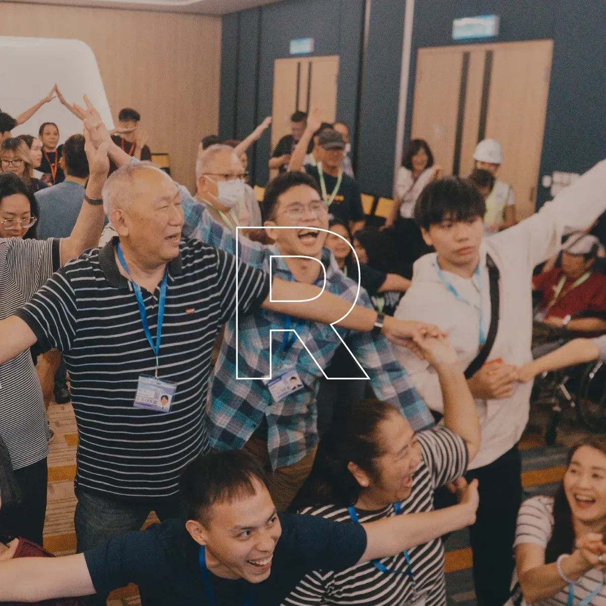 Crowd of people in a room raising hands and cheering during a lively group activity