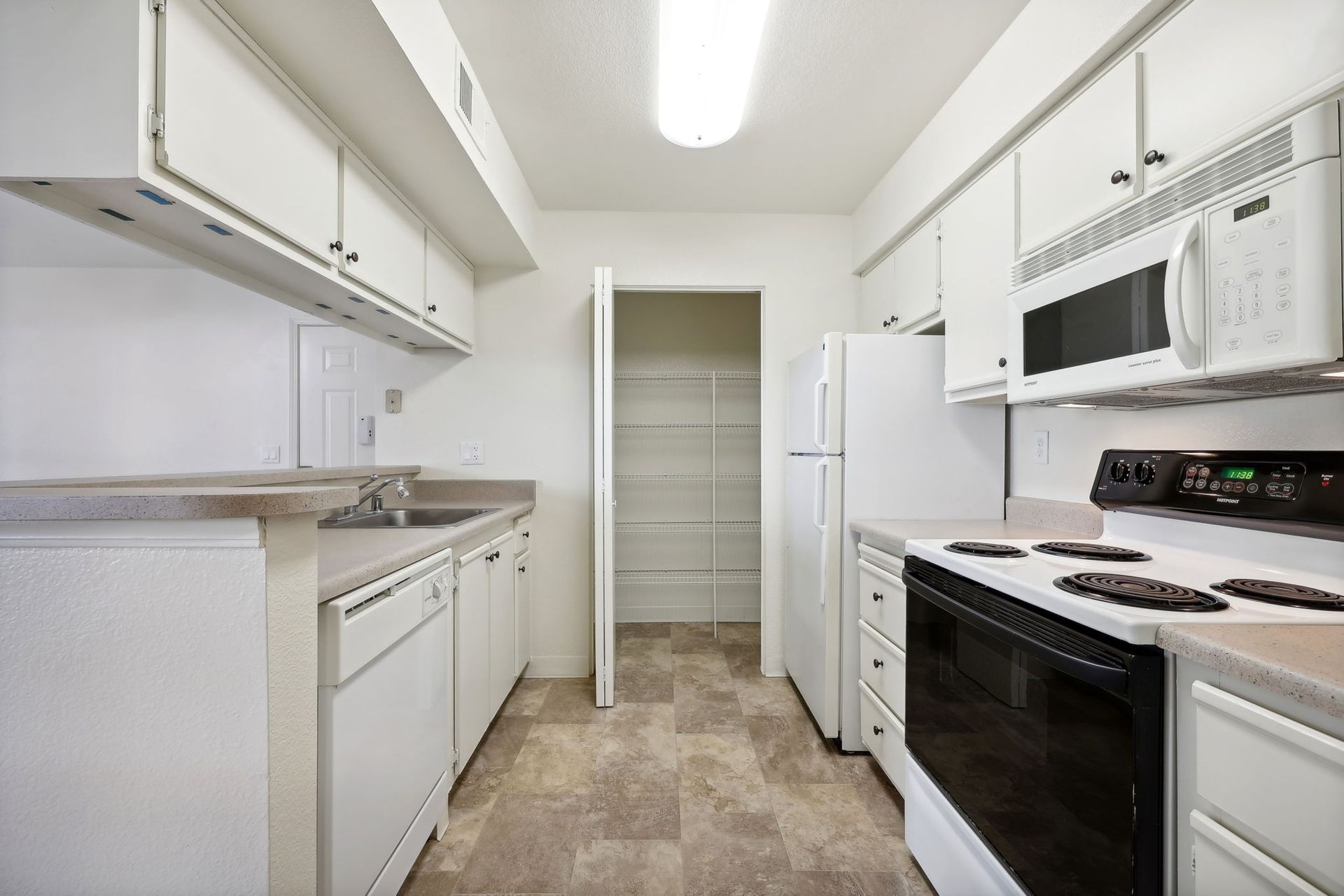 White kitchen with cabinets, appliances, and pantry.
