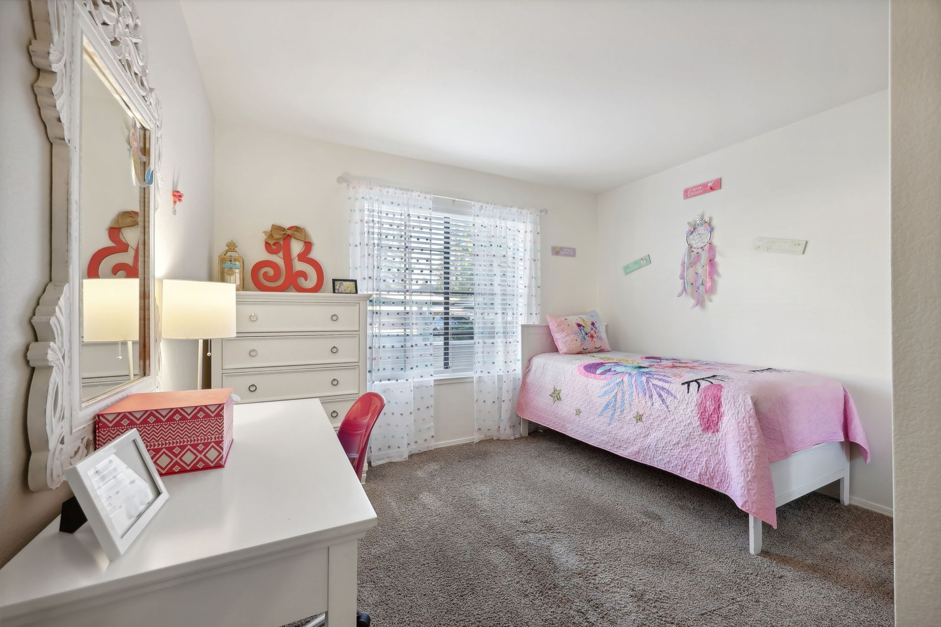 Bedroom with white furniture, pink accents, window, and a bed with a floral quilt.