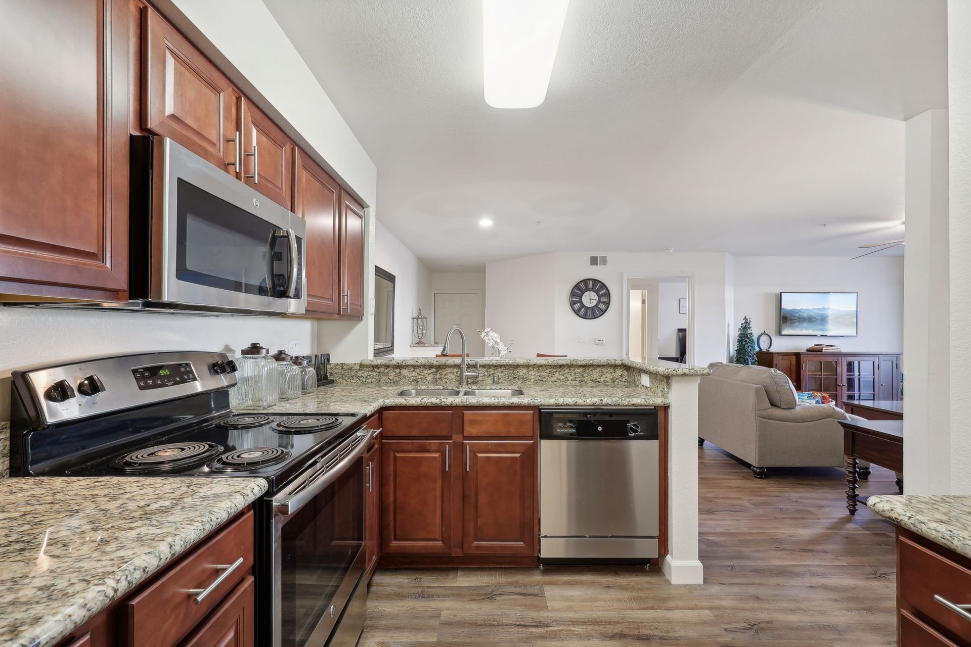 Kitchen with granite countertops, stainless steel appliances, and view into living area with a couch.