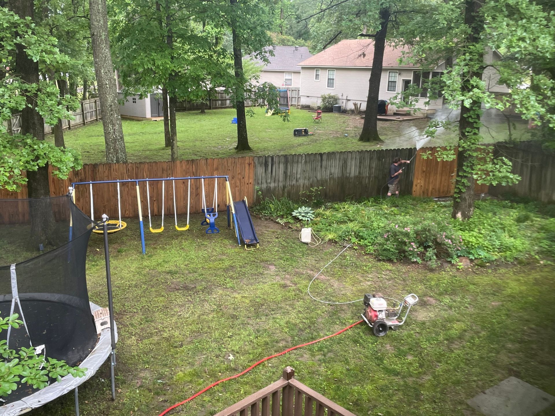 A backyard with a trampoline , swings , and a lawn mower.