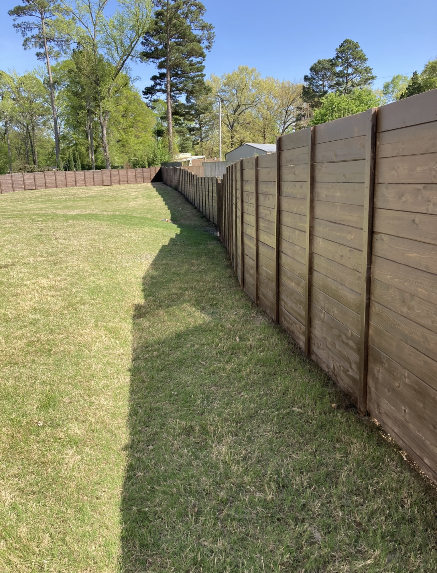 A wooden fence surrounds a lush green field.