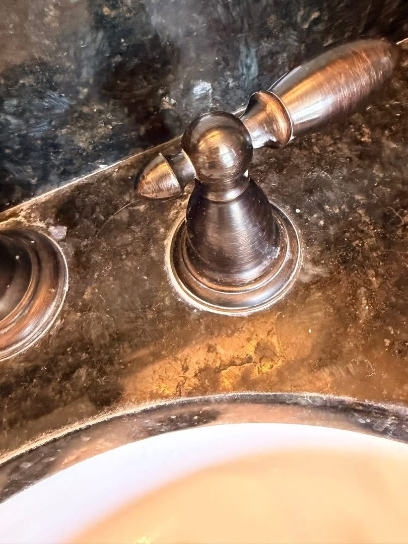 Metal faucet handle with wooden lever on a bathroom sink counter