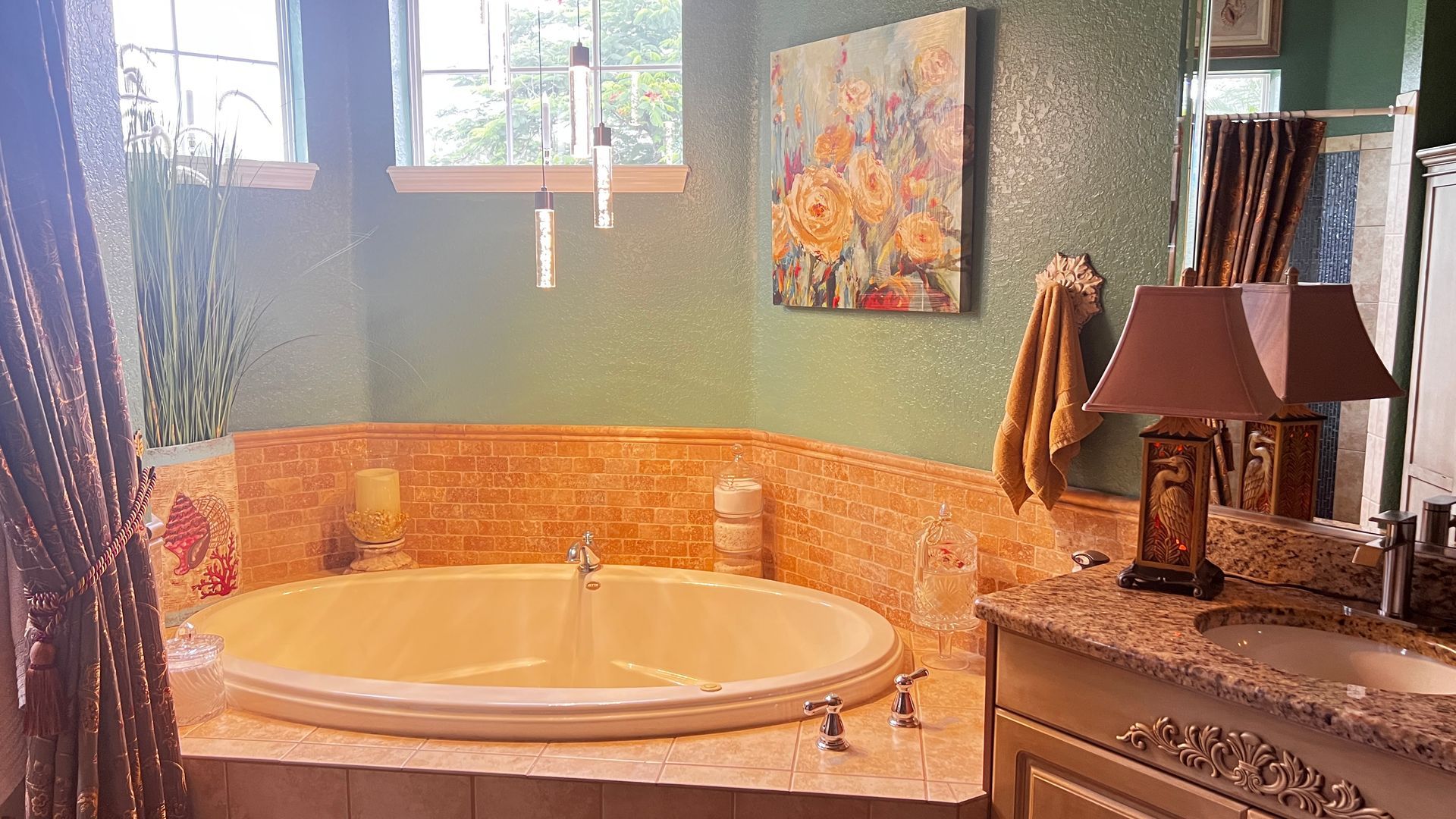 Spa bathroom with a round soaking tub, warm orange tile, green walls, and sunlight from a small window