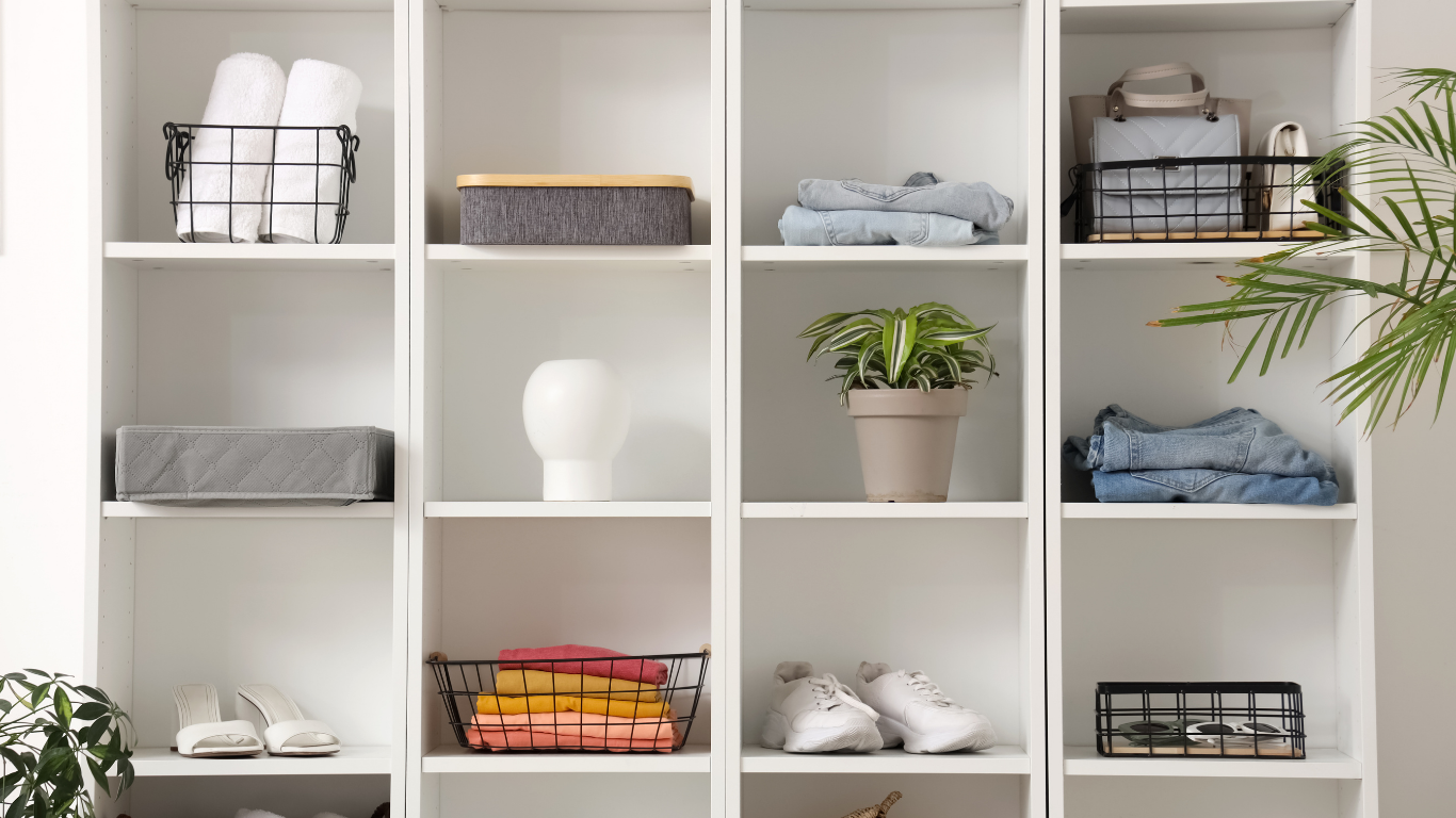 White shelving unit with folded towels, baskets, plants, and neatly stacked linens
