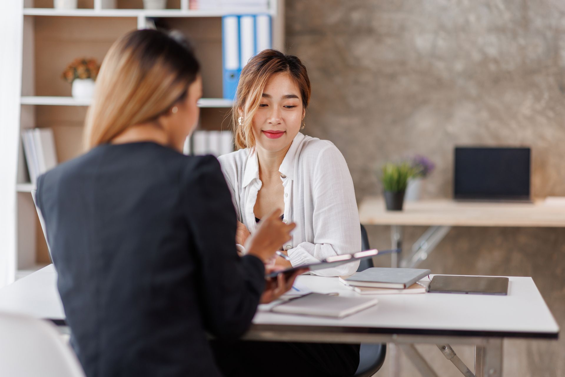 Dos mujeres están sentadas en una mesa conversando.