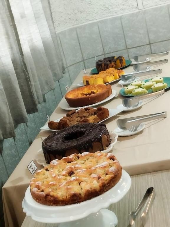 Buffet de sobremesas com bolos e doces em uma mesa comprida, visto de um ângulo.
