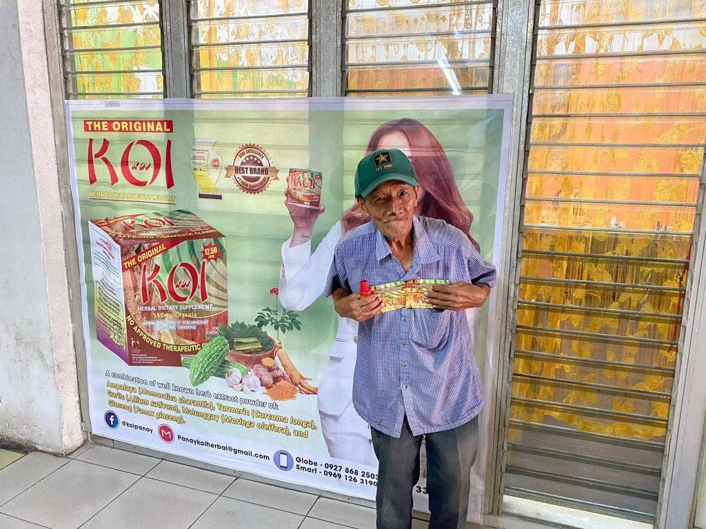 A man is standing in front of a sign holding a box of food.